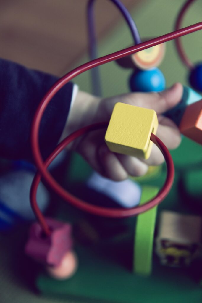 Dora e një fëmije të vogël duke luajtur me një lodër edukative me labirint rruaza